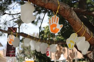 Photograph of painted hands hanging from a tree branch