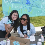 Two women pose with a puzzle piece in support of autism awareness.