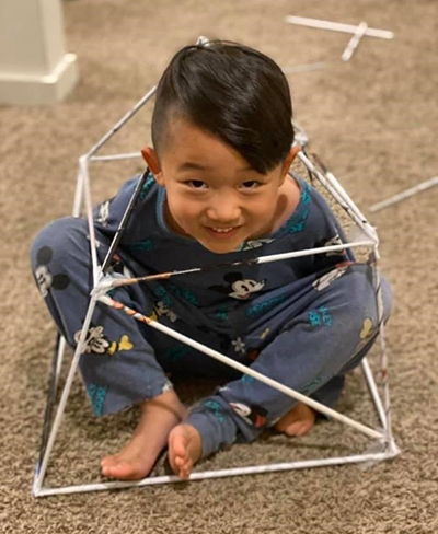Smiling child sitting inside homemade square geodesic dome
