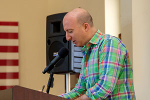 Man in a plaid shirt at a lectern.