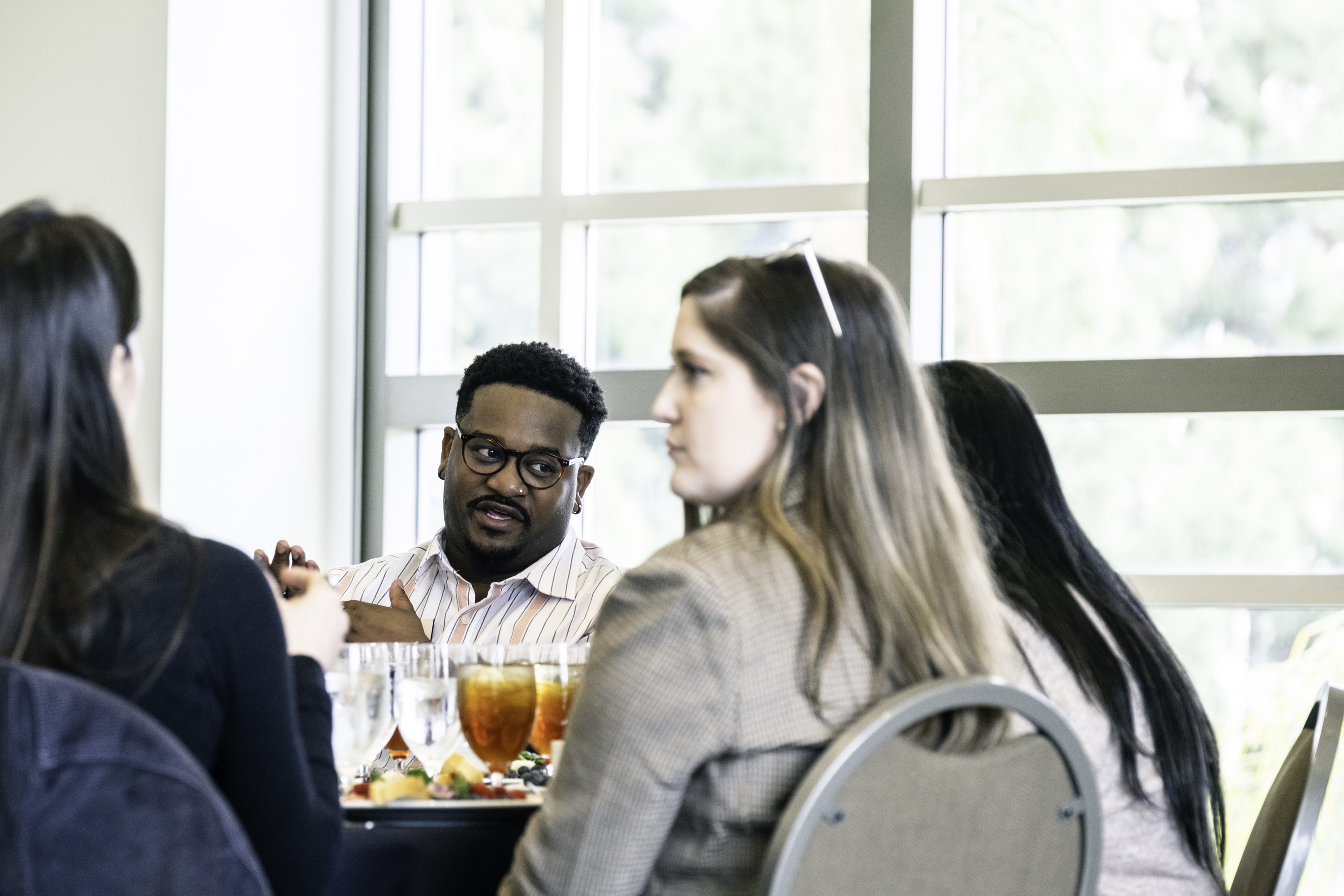 Photograph of a member of the Black Law Students Association speaking with prospective students at the Scholars Weekend luncheon