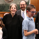 Photograph of Chapman alumna and Judge, Jennifer Feige, pictured in her robes with her family at her formal swearing-in event.
