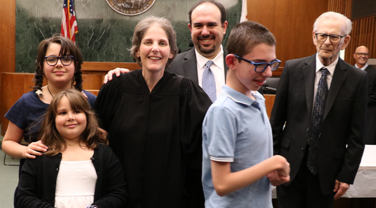 Photograph of Chapman alumna and Judge, Jennifer Feige, pictured in her robes with her family at her formal swearing-in event.