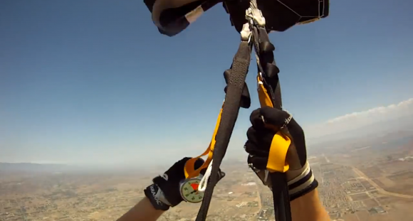 Skydiver's perspective of their hands and the parachute ropes as they descend