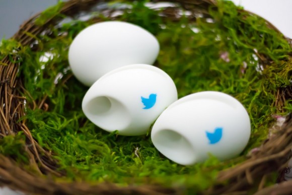 Three white eggs with the blue Twitter bird logo on them in a fake bird's nest