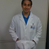 Mike stands wearing a white coat.