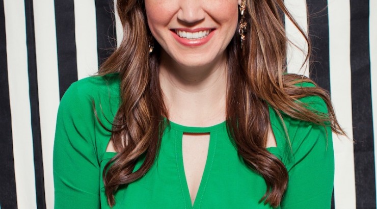 Naomi smiling in a green blouse with a black and white striped background