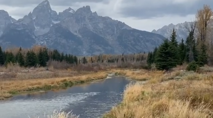 mountains in the distance with a river and brown grass in the foreground