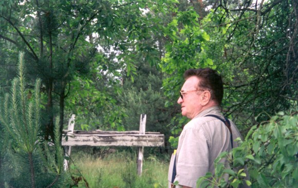 Thomas Blatt standing in a field, visiting the end of the tracks at Sobibor