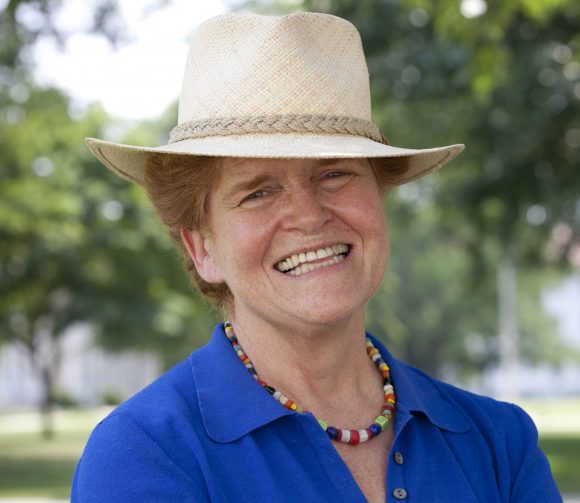 Photo of Deborah Lipstadt wearing a blue blouse, multicolored bead necklace and beige fedora