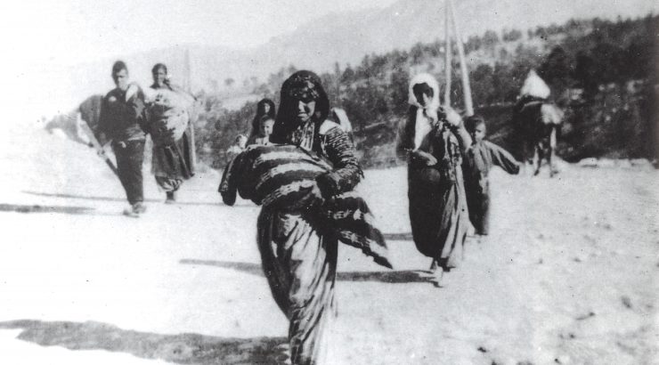 Photo of a woman carrying a bundled child while marching during the Armenian genocide in the Ottoman Empire