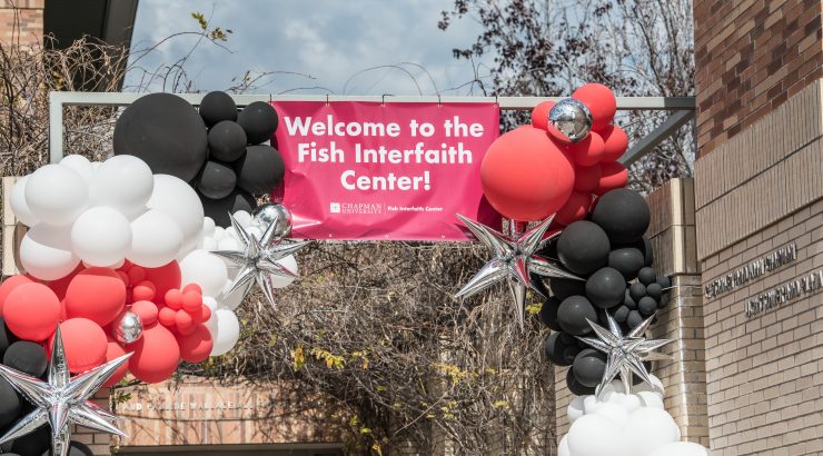 Banner that says Welcome to the Fish Interfaith Center surrounded by black red and white balloons