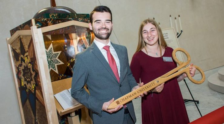 Two student workers holding giant scissors