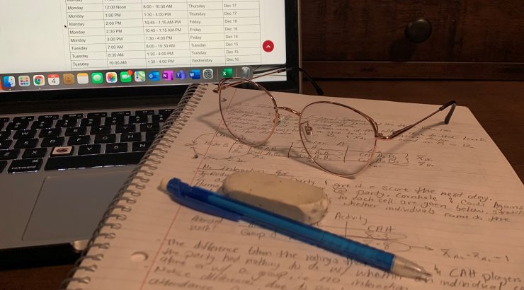 notebook with glasses and a pen in front of a laptop