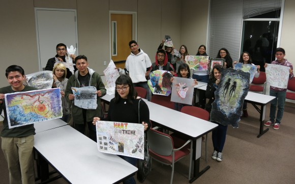 students holding artwork in a classroom