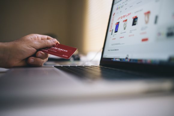 Picture of a laptop and a hand holding a credit card