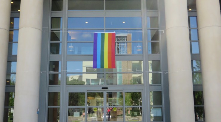 A rainbow pride flag hangs from the main entryway to the Leatherby Libraries.