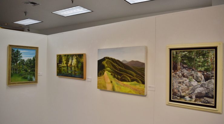 Photograph of four paintings hanging on a wall