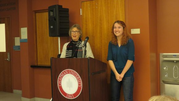 A middle-aged woman stands behind a podium talking while a young woman stands to the right of the podium.