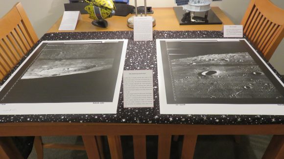 Two photographs of the moon's surface displayed on a wooden table over a moon and star patterned scarf