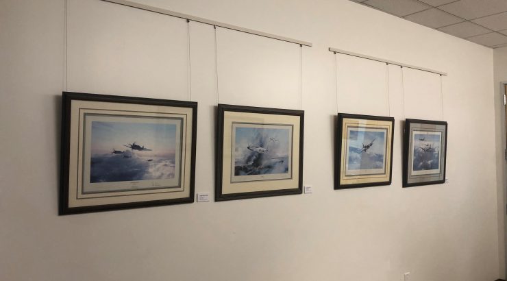 Four lithographs of aircraft hanging on a white wall.