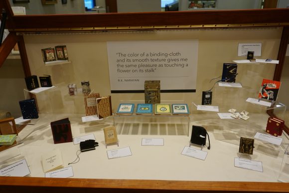 A horizontal display case containing a variety of miniature books