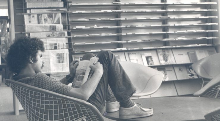 Black and white picture of a male student reading a book in the Thurmond Clarke Memorial Library