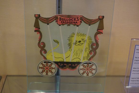 A die-cut children's menu in the shape of a wagon, with an illustration of a lion inside the wagon.
