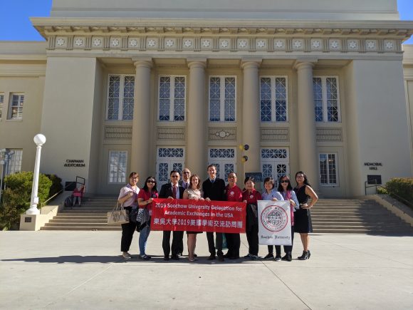 Soochow visitors and CGE students holding Soochow flag in front of Chapman library